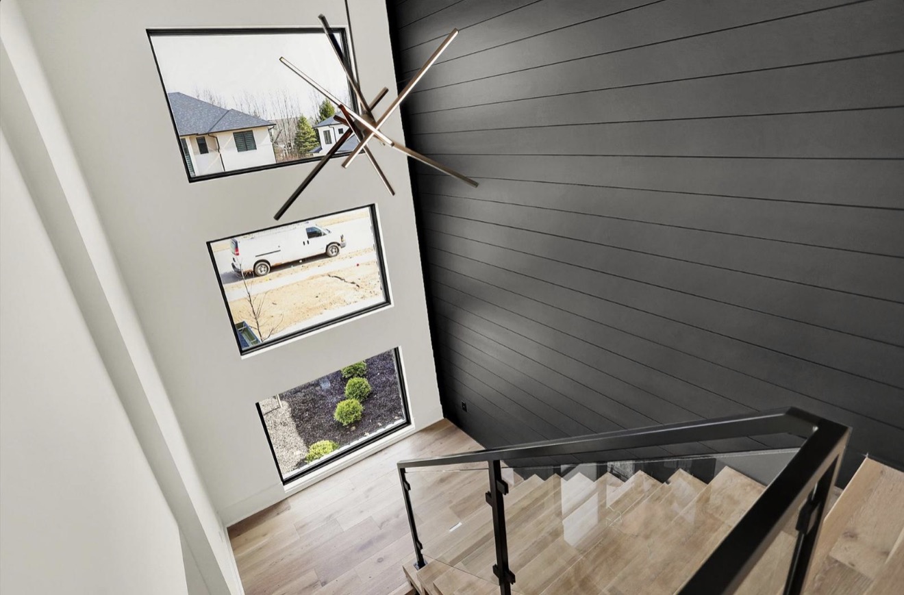 Open stairwell with glass railing, stacked windows and a charcoal shiplap accent wall