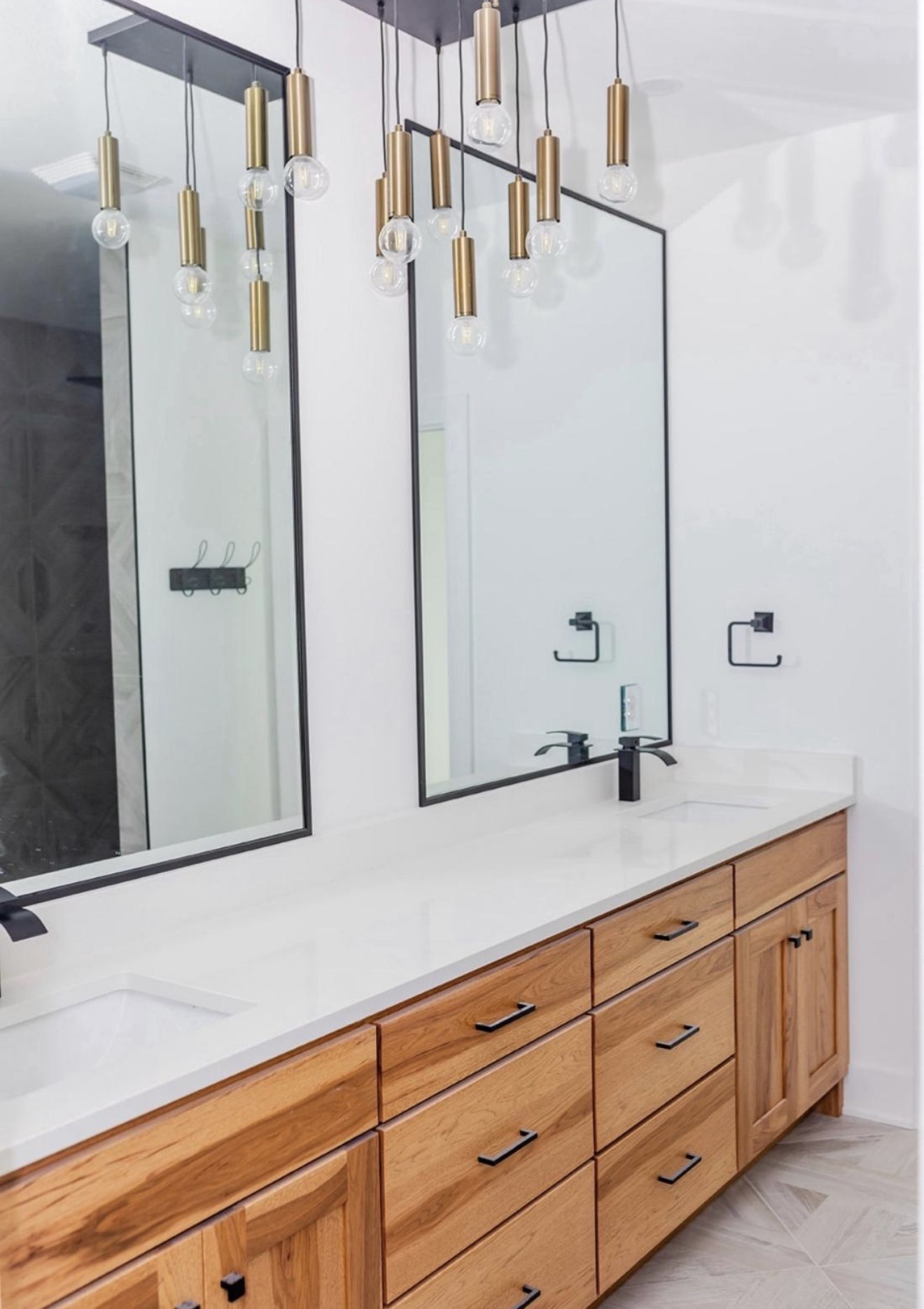 Guest bath with natural hickory double vanity, black framed mirrors and brass pendant lighting