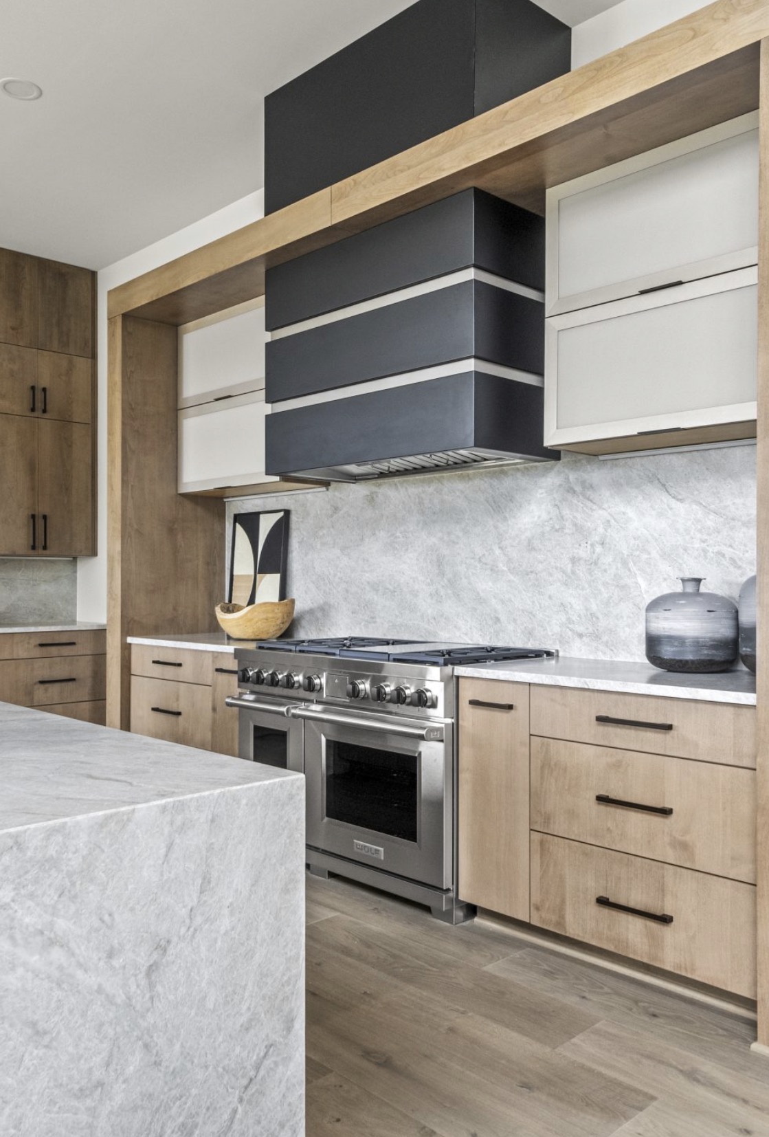 Contemporary kitchen with rift white oak cabinetry, honed marble backsplash and a matte black custom range hood
