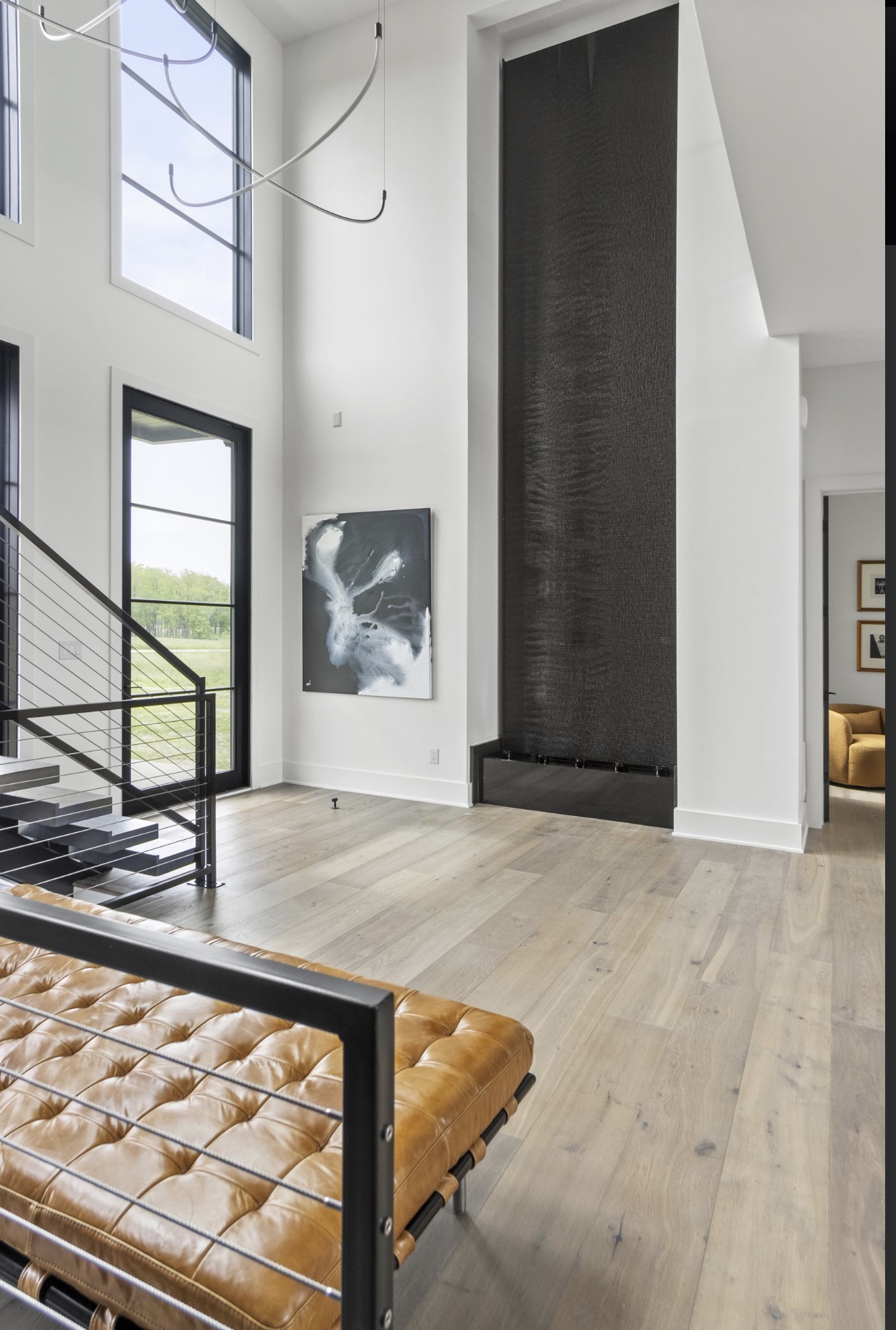 Two story entry foyer with black steel and cable stair railing, textured charcoal feature wall and white oak floors