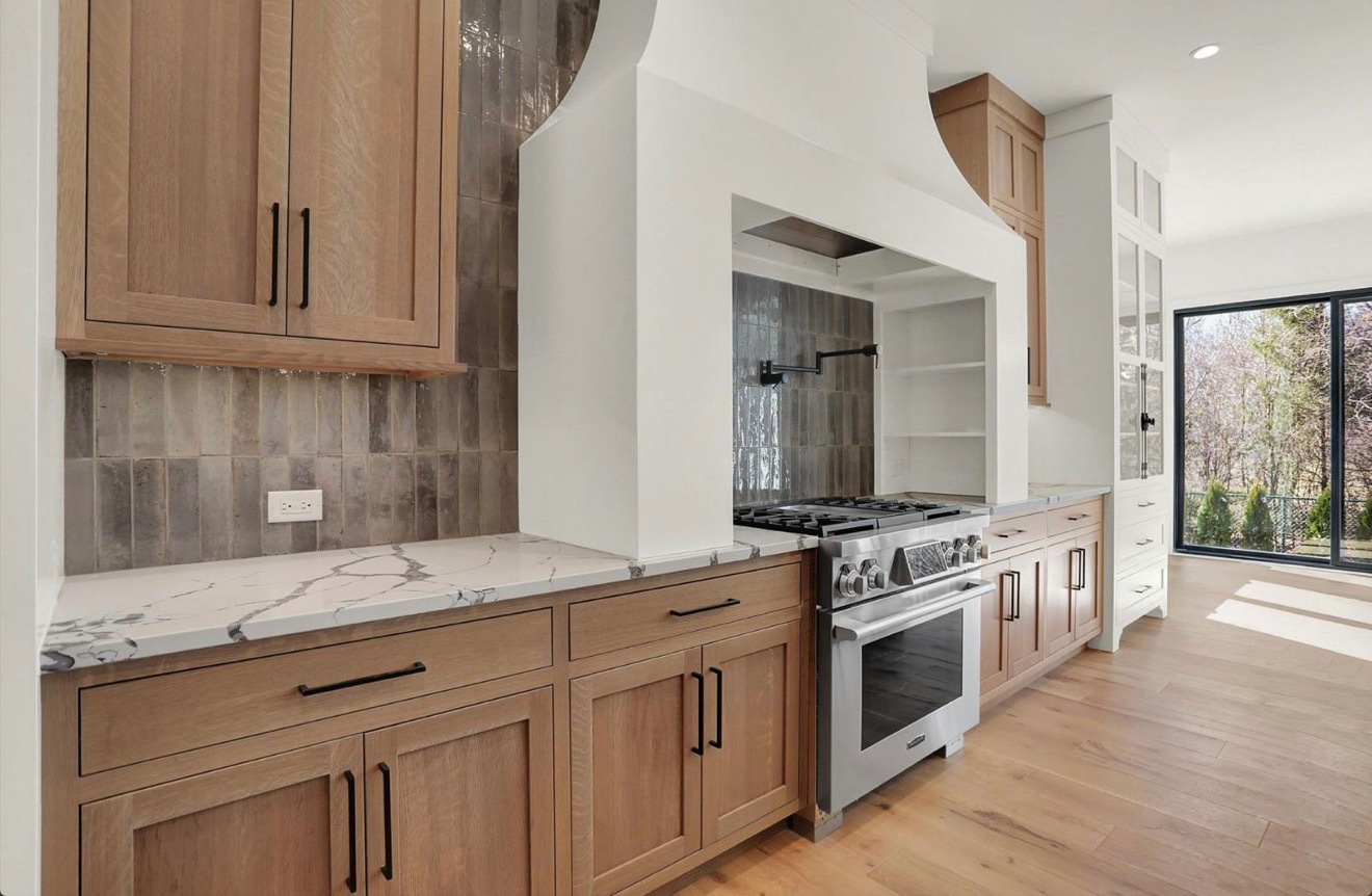 Custom kitchen with white oak cabinetry, quartz waterfall counters and a professional gas range