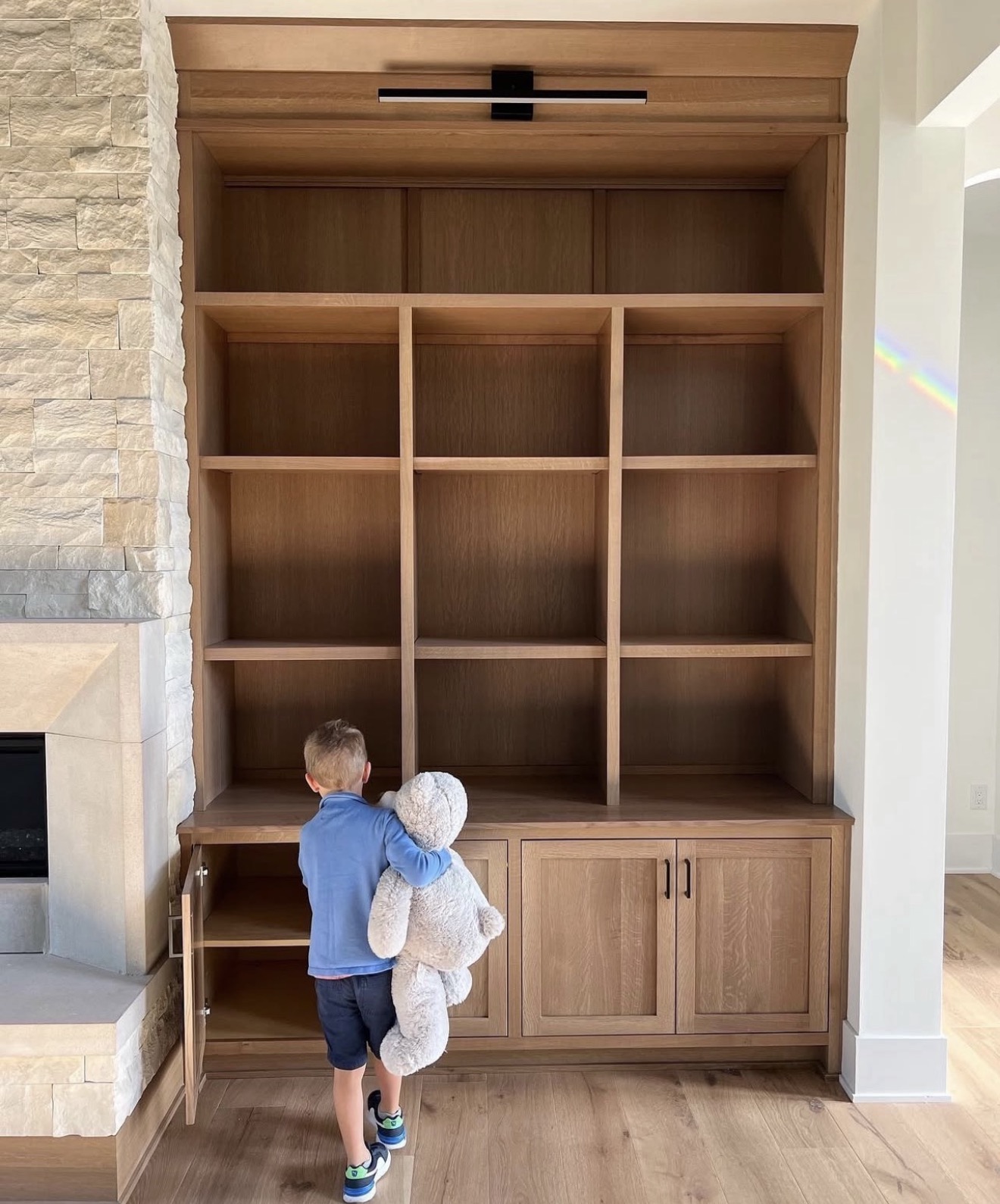 White oak built in shelving and cabinetry flanking a stacked stone fireplace