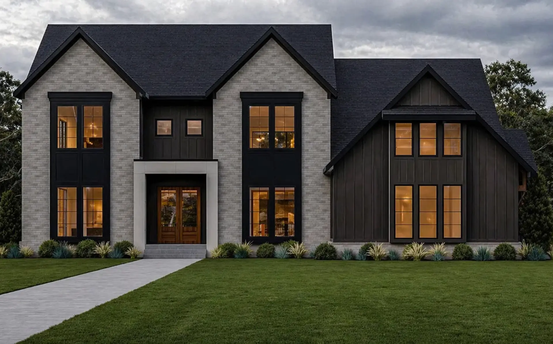 Two story custom home exterior with gray brick, black trim and warm glowing windows at dusk