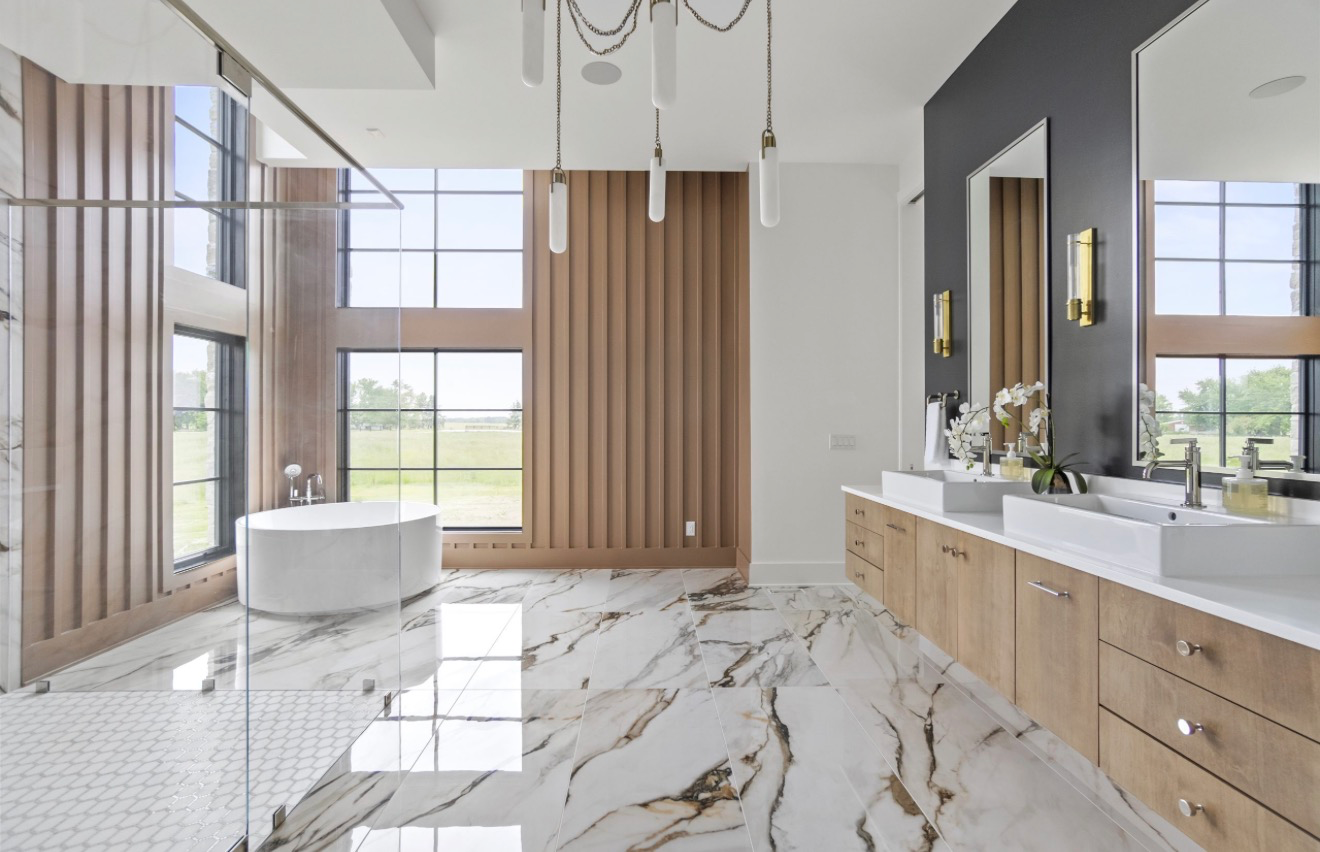 Luxury primary bathroom with marble floors, freestanding soaking tub, white oak vanity and brass sconces